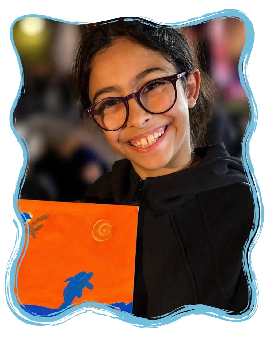A child proudly holding their painting