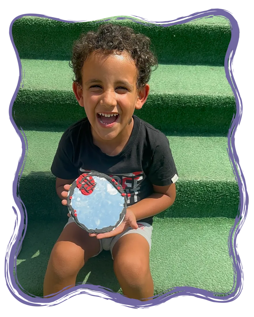 A happy child showing their craft at Playtopia